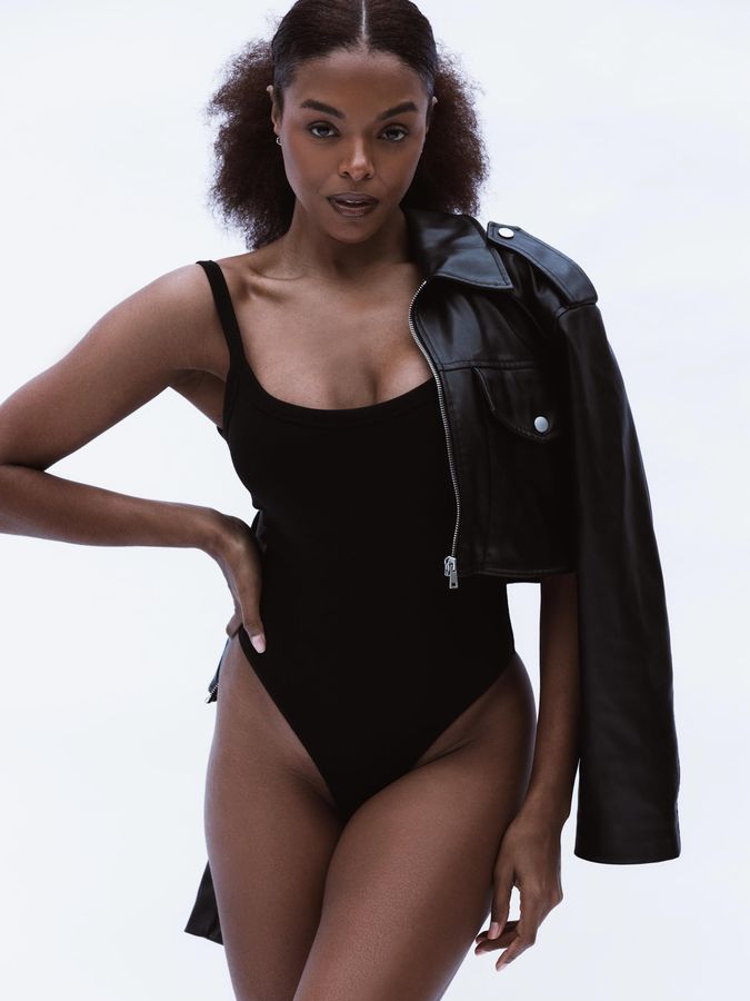 Modelo em body preto e jaqueta de couro fotografada em fundo branco